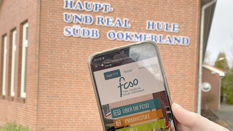 Die Internetseite der FCSO, aufgerufen auf einem Smartphone, vor dem Gebäude der ehemaligen Haupt- und Realschule in Moordorf. Foto: Holger Janssen