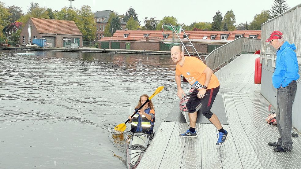 Daniela Jungenkrüger legt mit dem Kajak am Steg im Auricher Hafen an. Dort wartet ihr Mitstreiter Jan Niklas Neldner. Er wird per Handschlag auf die Laufstrecke geschickt. Fotos: Gerd-Arnold Ubben
