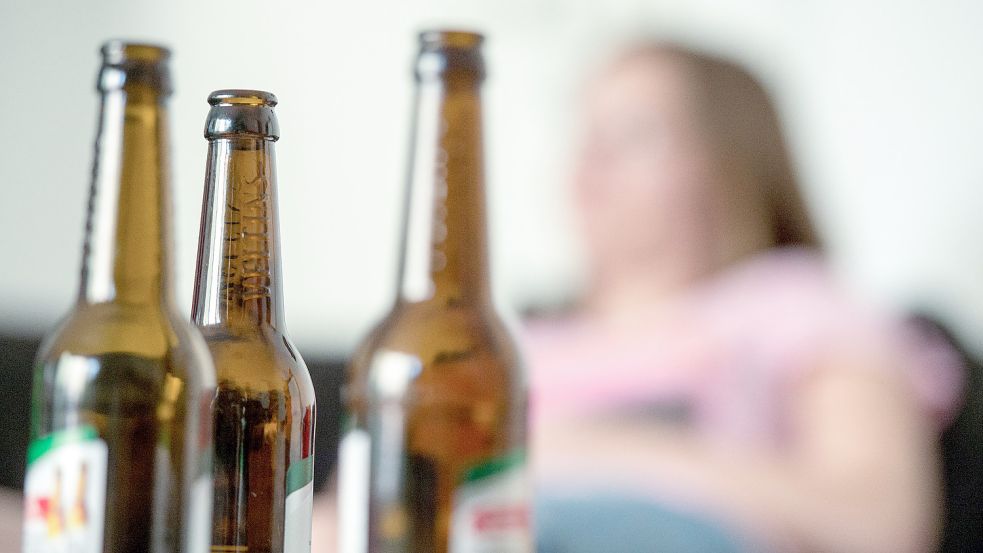 Eine junge Frau sitzt hinter leeren Bierflaschen. Die Corona-Pandemie erhöht Experten zufolge das Risiko für Alkohol- und Drogenmissbrauch. Foto: DPA
