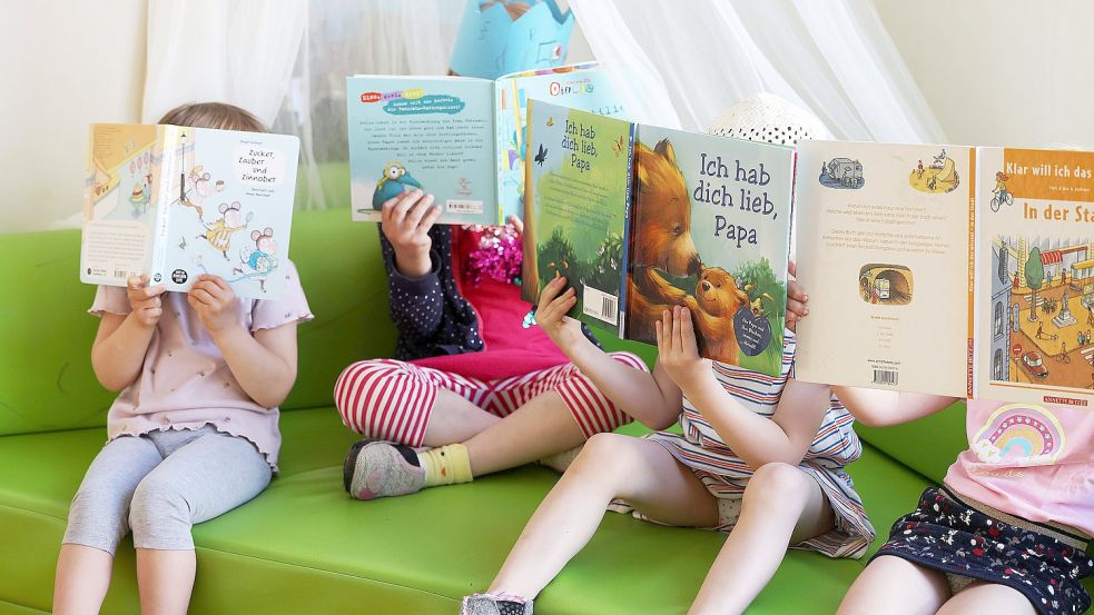 Kinder sitzen mit Büchern auf einem Sofa. Foto: DPA