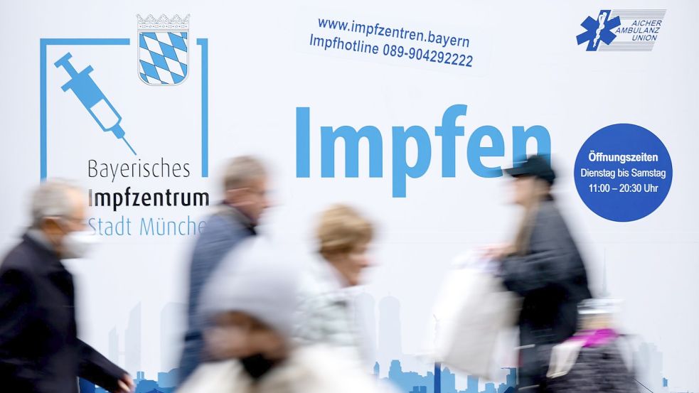 Passanten gehen an einem Impfzentrum in der Münchener Innenstadt vorbei. Foto: Sven Hoppe/dpa