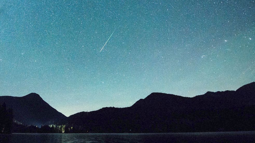 Eine Sternschnuppe leuchtet neben der Milchstraße am Himmel über dem Walchensee. Foto: Matthias Balk/dpa