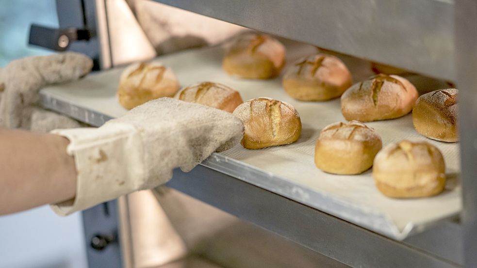 Ein Bäcker holt Brötchen aus einem Ofen. Foto: Fabian Sommer/DPA