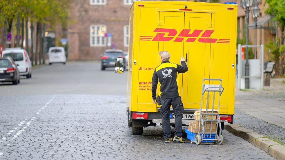 Ein Zusteller entlädt ein Fahrzeug von DHL in Lüneburg. Foto: Philipp Schulze/dpa