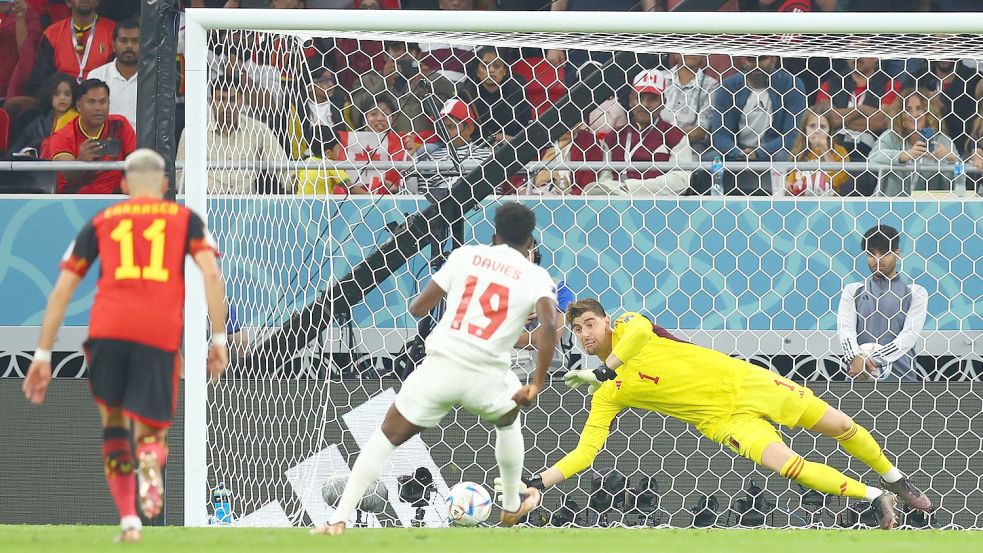 Belgiens Torwart Thibaut Courtois (r) hält den Strafstoß des Kanadiers Alphonso Davies (M/19). Foto: Tom Weller/dpa