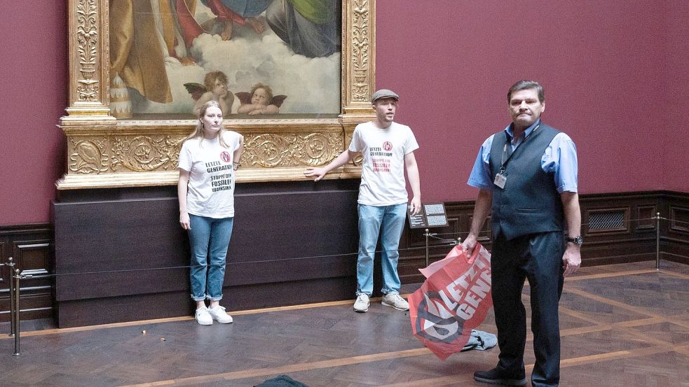 Zwei Umweltaktivisten der Gruppe „Letzte Generation“ stehen in der Gemäldegalerie Alte Meister am Gemälde „Sixtinische Madonna“ von Raffael. Foto: Sebastian Kahnert/dpa