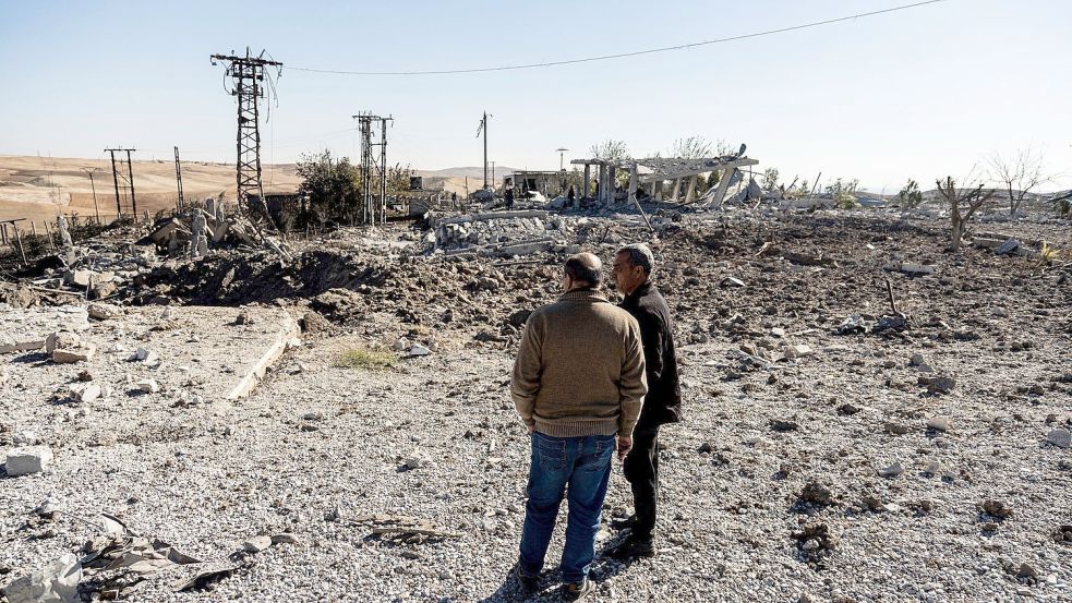 Zwei Männer begutachten Schäden in einem Gebiet um ein Elektrizitätswerk in Nordsyrien nach türkischen Luftangriffen. Foto: Baderkhan Ahmad/AP/dpa
