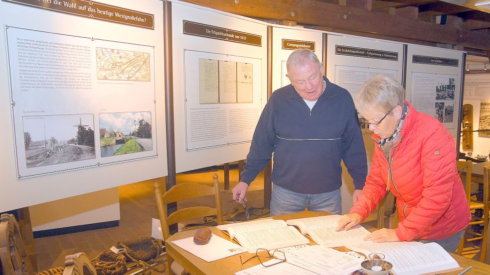 Helmut von Aswege und Marlene Hedemann sehen sich im Fehnmuseum Eiland ein Ortssippenbuch an. Foto: Gerd-Arnold Ubben