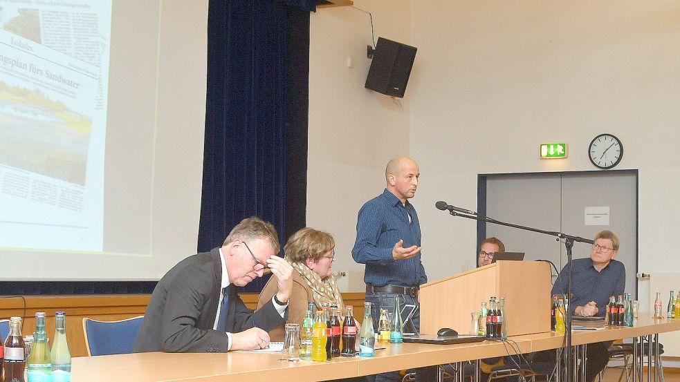 Der Limnologe Tim Epe (stehend) während seines Vortrags, vorne Ihlows Bürgermeister Arno Ulrichs und seine Baudezernentin Annette Lang, hinten Vertreter der Emder Stadtwerke.