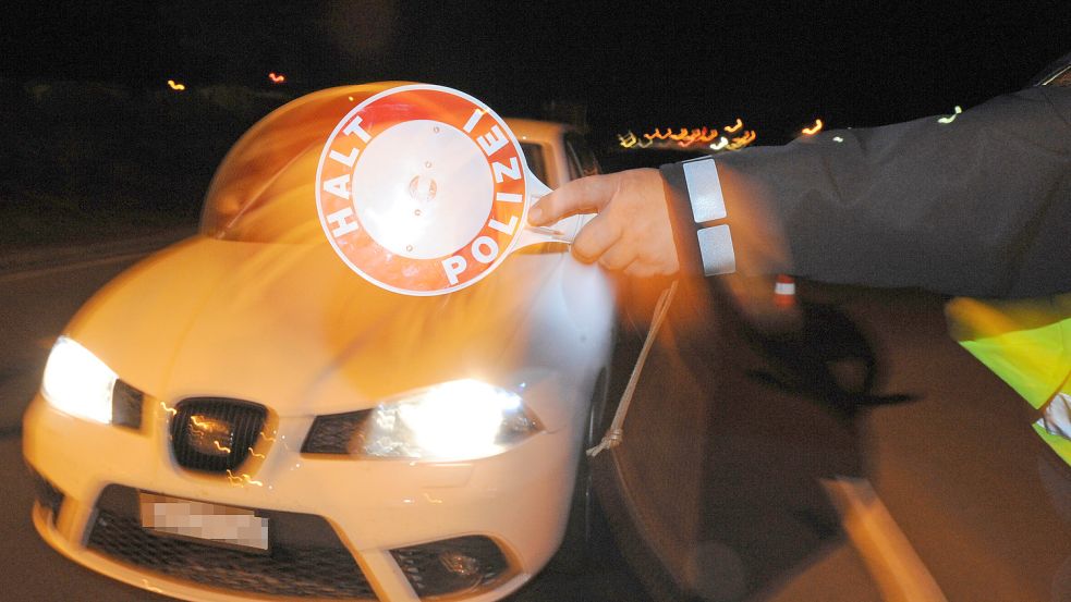 Ein Polizist winkt einen Autofahrer mit einer Kelle aus dem laufenden Verkehr. Foto: DPA