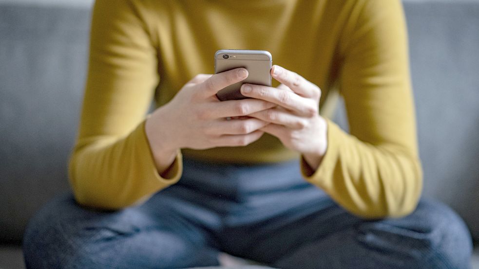 Eine junge Frau hält ein Smartphone in der Hand. Wie gut im Ernstfall amtliche Warnungen über Radio, Fernsehen, Apps oder Sirenen funktionieren würden, testen Bund, Länder und Kommunen am 8. Dezember beim bundesweiten Warntag. Foto: DPA