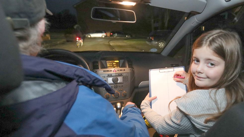 Deetje führt eine Liste während der Fahrt. Im Hintergrund sieht man einen Radfahrer, der dunkel gekleidet ist. Foto: Romuald Banik