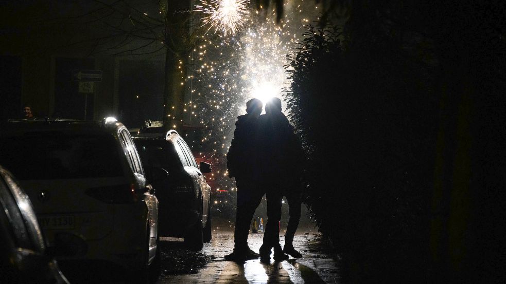 Mehrere Menschen schauen in einer Wohnstraße einem Feuerwerk zu. Foto: DPA