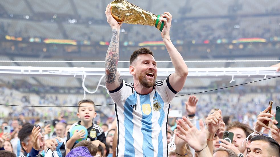 Argentiniens Lionel Messi lässt sich mit dem Weltmeisterpokal nach dem Finalsieg gegen Frankreich im Lusail Stadion in Katar feiern. Foto: DPA