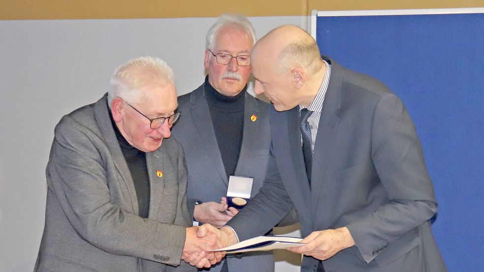 Hinrich Trauernicht (von links) erhielt vom Ratsvorsitzenden Detlev Schoone sowie von Bürgermeister Erwin Adams eine Ehrenmedaille und eine Urkunde. Foto: Heino Hermanns