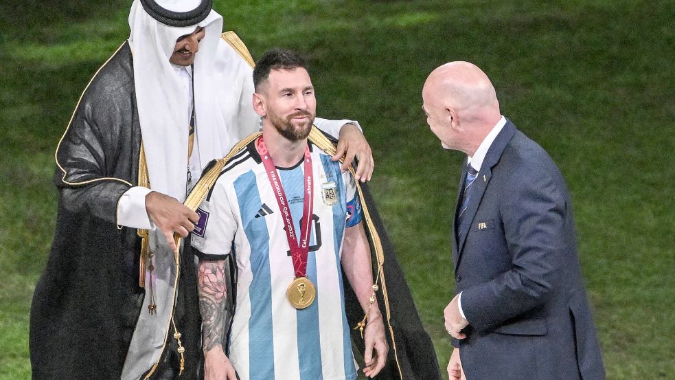 Umstrittene Aktion: Scheich Tamim bin Hamad Al Thani legt Lionel Messi vor Übergabe des WM-Pokals ein Bischt, ein traditionelles arabische Kleidungsstück, an. Foto: dpa/Robert Michael
