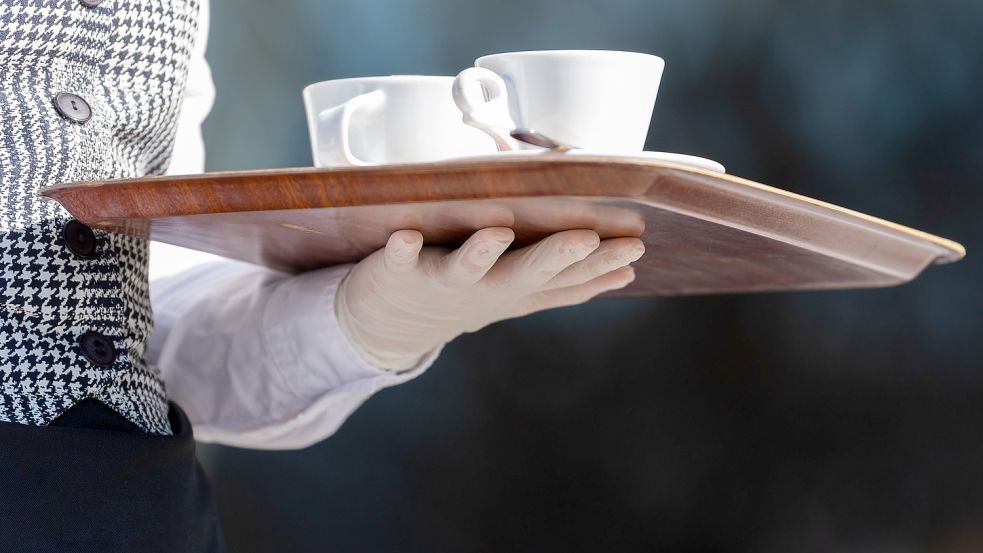 Ein Mann hält ein Tablett mit zwei Kaffeetassen. Foto: DPA