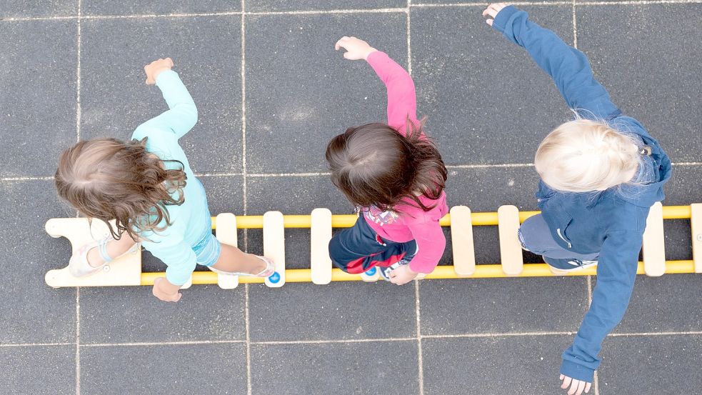 Kinder balancieren auf einer am Boden liegenden Leiter. Foto: DPA