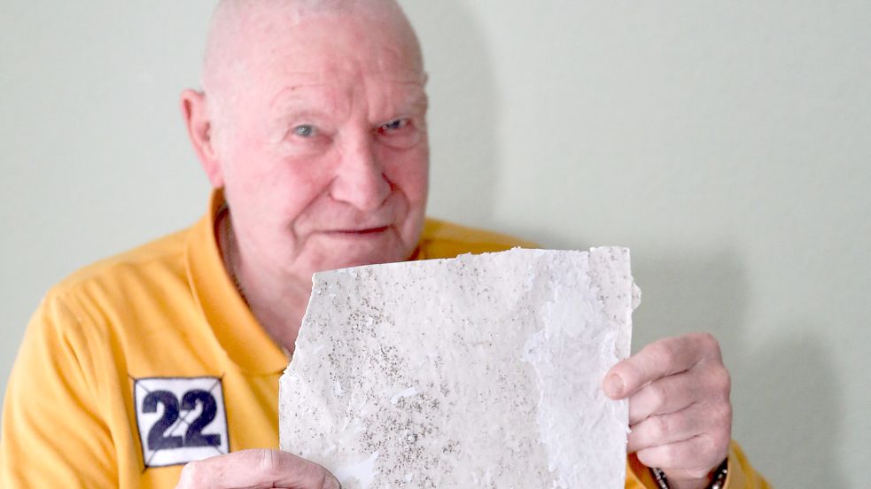 Herbert Fath hält die Rückseite eines Stücks Tapete hoch. Auf der Rückseite sind schwarze Verfärbungen zu erkennen. Foto: Romuald Banik