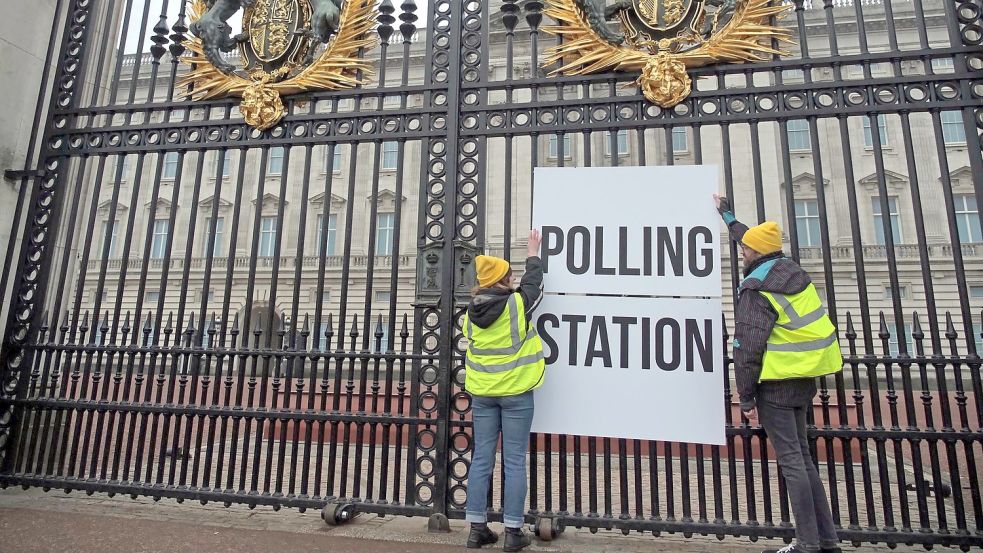 Anhänger der Kampagnengruppe Republic hängen ein Wahllokalschild ans Geländer des Buckingham Palace in London. Foto: Aaron Chown/PA Wire/dpa