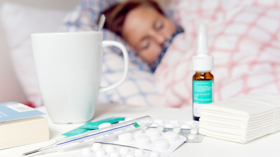 Medikamente und ein Fieberthermometer liegen in einer gestellten Szene auf einem Nachttisch. Foto: DPA