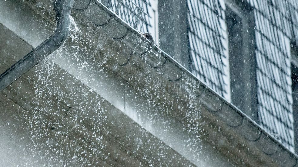 Regenwasser fließt während eines Unwetters an einer überfüllten Regenrinne hinunter. Foto: DPA