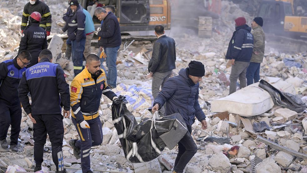 Zwei Männer tragen eine Leiche aus einem zerstörten Gebäude. Mehr als 13 Millionen Menschen in der Türkei sind nach Einschätzung der Regierung von der Erdbebenkatastrophe betroffen. Foto: DPA