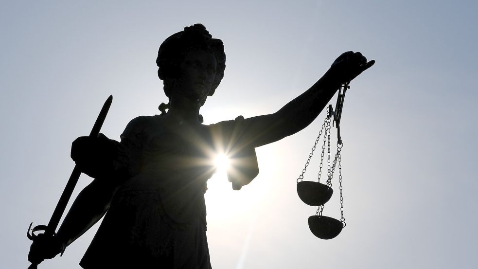 Eine Statue der römischen Göttin der Gerechtigkeit, Justitia, mit Schwert und Waage als Schattenriss vor der Sonne. Foto: DPA
