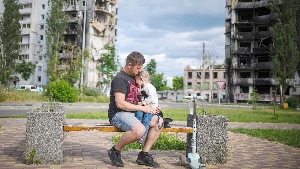 Ein Mann sitzt mit seiner Tochter vor zerstörten Häusern in Borodjanka. Foto: DPA