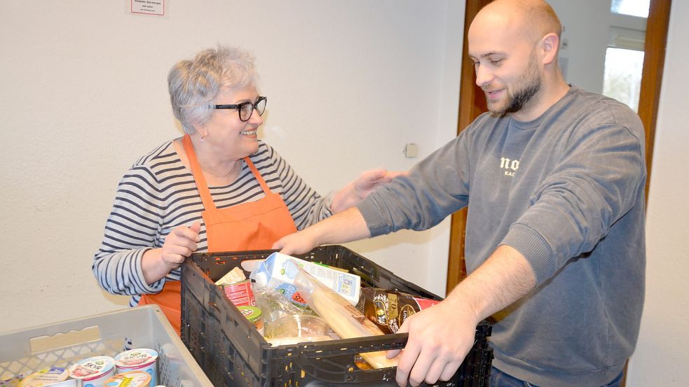 Lidia Schmidt packt bei der Tafel in Aurich Kisten mit Lebensmitteln, die Sven Duderstadt an die Tafelkunden weiterreicht. Foto: Franziska Otto