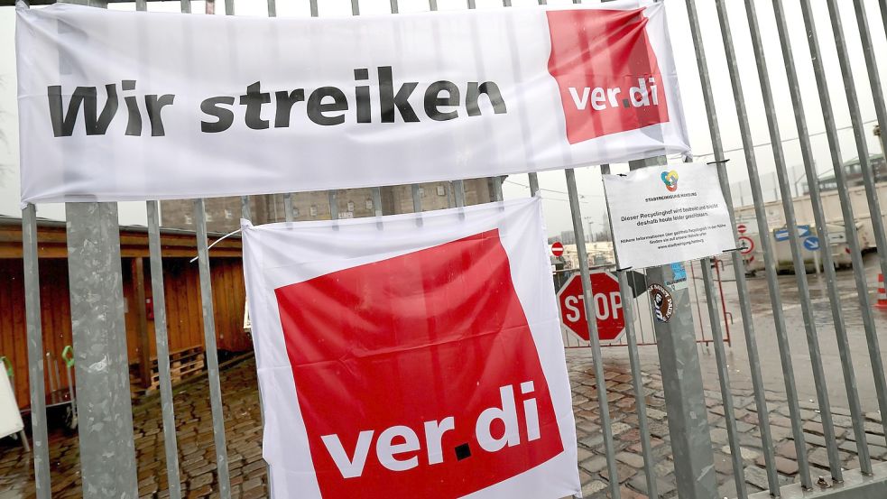 Streikplakate von Verdi hängen bei einer Abschlusskundgebung zu ihrem Warnstreik vor den geschlossenen Toren eines Recyclinghofs. Foto: DPA
