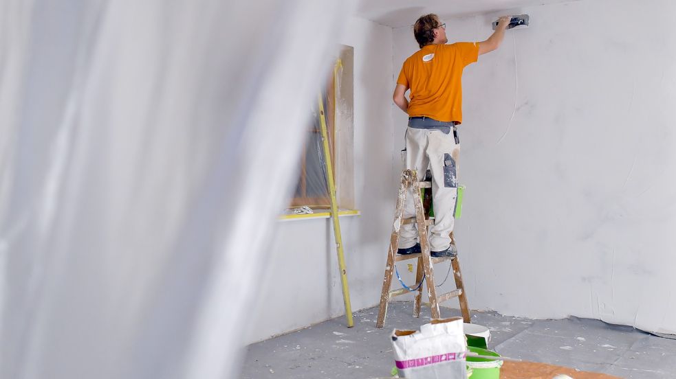 Ein Maler renoviert ein Wohnzimmer: Einige Handwerksbetriebe in Aurich bieten ihren Mitarbeitern mittlerweile flexiblere Arbeitszeiten an. Foto: DPA