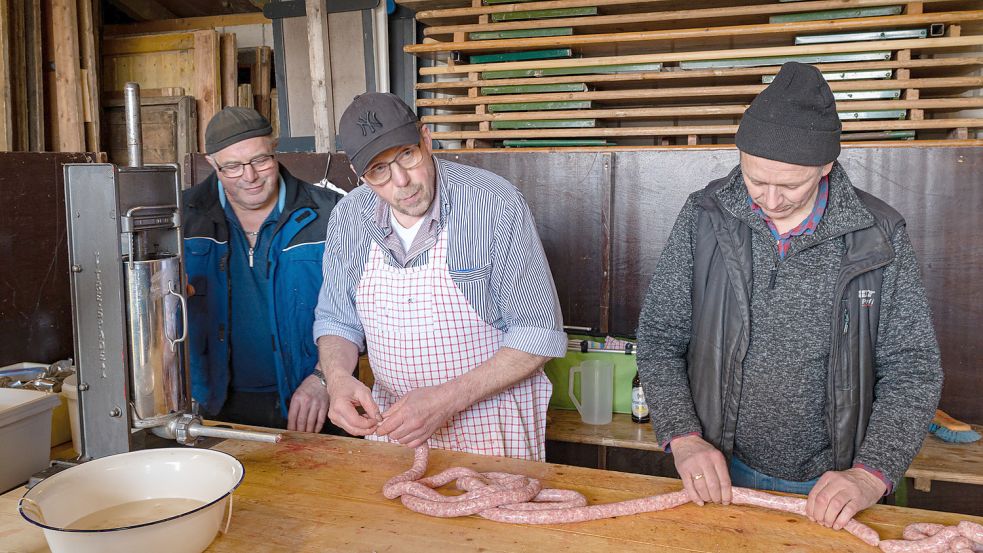 Johann Heinks (links) und Jann Wunder (rechts) gingen Schlachter Hero Bergmann beim Mettwurstpressen zur Hand. Foto: Folkert Bents