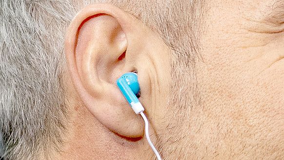 Ein Mann trägt In-Ear-Kopfhörer. Foto: DPA