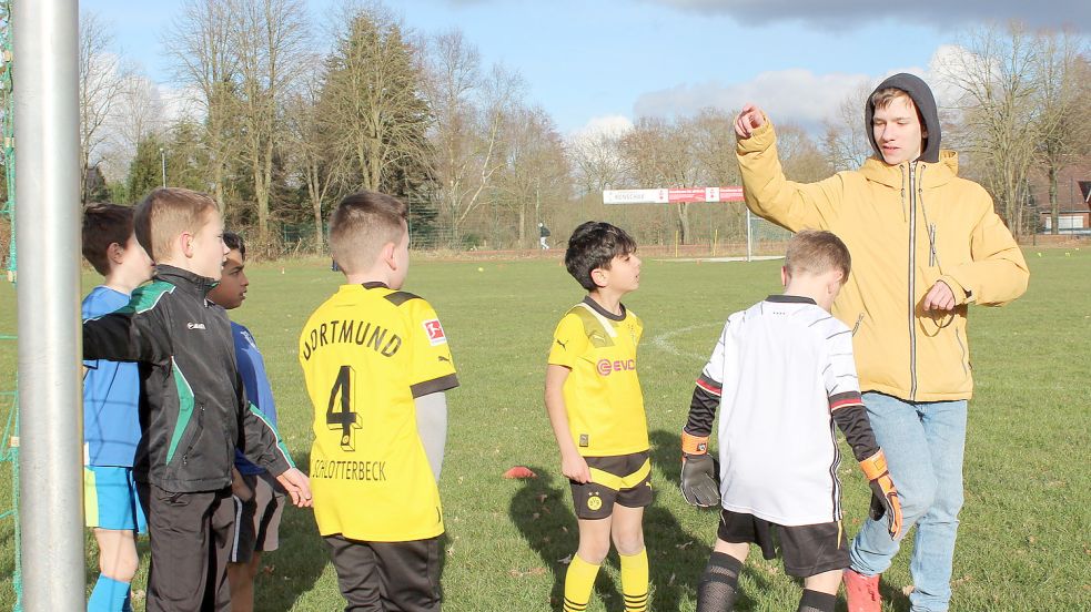 Pascal Lütje (rechts) teilt die Kinder in Pärchen ein, die sich gegenseitig den Ball zupassen und auf das Tor schießen sollen.