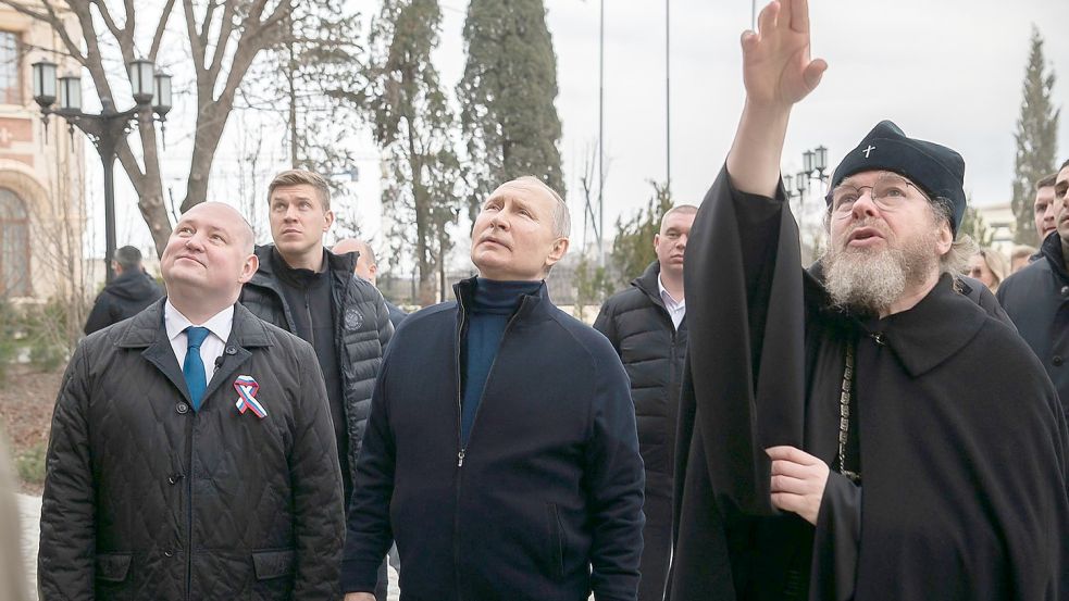 Kremlchef Putin ist zum neunten Jahrestag der russischen Annexion der Krim zu einem unangekündigten Besuch auf der Schwarzmeer-Halbinsel eingetroffen. Hier zusammen mit dem Gouverneur von Sewastopol, Michail Raswoschajew und Bischof Tichon beim Besuch einer Kunstschule für Kinder. Foto: Uncredited/Pool Sputnik Kremlin/AP/dpa