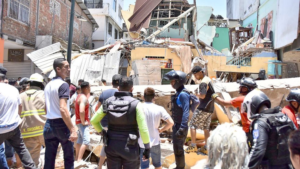 Anwohner und Rettungskräfte stehen vor zerstörten Gebäuden in Machala. Foto: Jorge Sanchez/AP/dpa