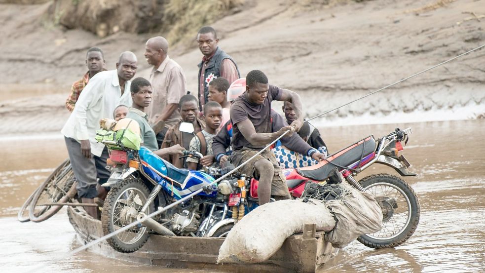 Männer transportieren in Malawi ihre geretteten Habseligkeiten mit einem Holzboot. Foto: Thoko Chikondi/AP