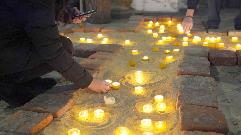 Menschen zünden Kerzen anlässlich des Gedenkgottesdienstes für die Opfer des Amoklaufs bei den Zeugen Jehovas in Hamburg an. Foto: Marcus Brandt/dpa/Pool/dpa