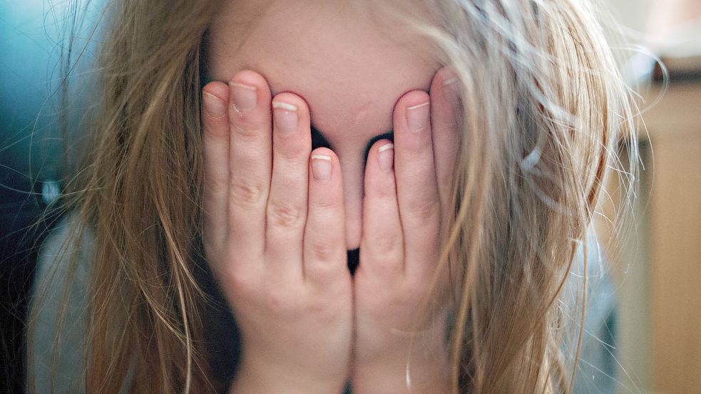 Ein junges Mädchen hält sich in einer gestellten Szene die Hände vor ihr Gesicht. Foto: DPA