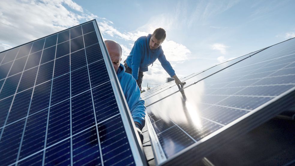 Arbeiter installieren eine Photovoltaikanlage auf einem Dach. Foto: Marijan Murat/DPA