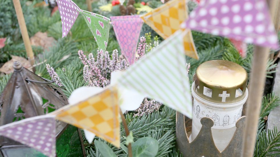 Auf einem Kindergrab im "Garten der Sternenkinder", dem Teil des Friedhofs des Alten St.-Matthäus-Kirchhofs in Berlin für gestorbene Kinder, sind bunte Wimpel und ein Grablicht zu sehen. Foto: Stephanie Pilick/dpa