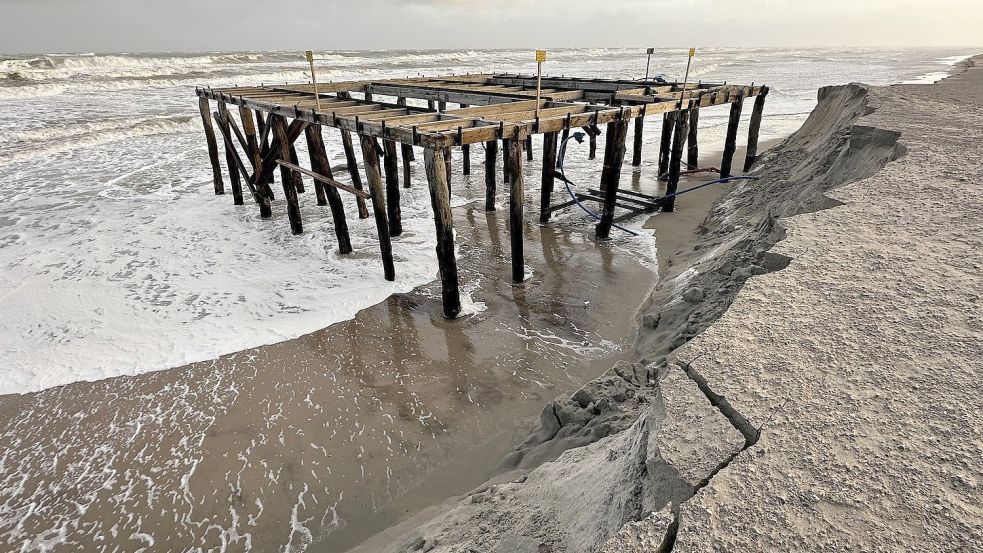 Wellen umspülen im Februar bei stürmischem Wetter am Strandabschnitt „Weiße Düne“ auf Norderney ein Holzgerüst für Umkleidekabinen und die Badeaufsicht. Das Gerüst ist in den Sommermonaten mit Sand zugeschüttet. Sturmfluten haben den Sand weitgehend abgetragen. Foto: DPA