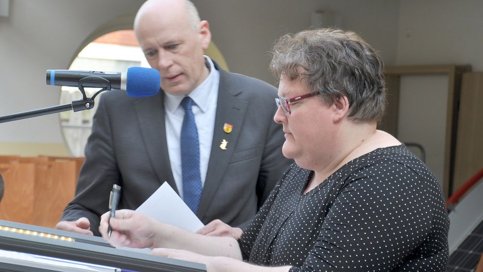 Claudia Oltrop unterschreibt unter den Augen des Fehntjer Bürgermeisters Erwin Adams ihre Verpflichtung für die Ratsarbeit. Foto: Kim Hüsing