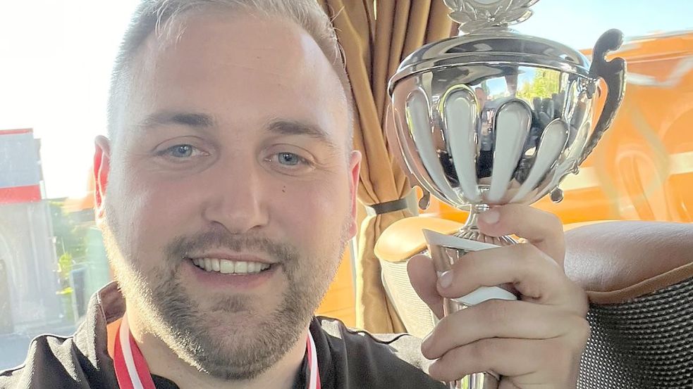 Marco Peters präsentierte die Trophäe für die im Endspiel unterlegenen Moordorfer Darter. Als Bonbon gab es noch das Ticket für die Teilnahme am Verbandspokal oben drauf.