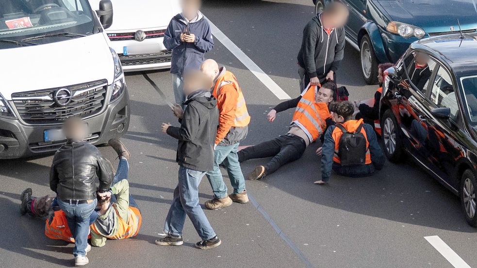 Bürger machen den Weg frei: Immer wieder führen die Blockaden der „Letzten Generation“ zu Ärger. Foto: dpa/Hannes P Albert