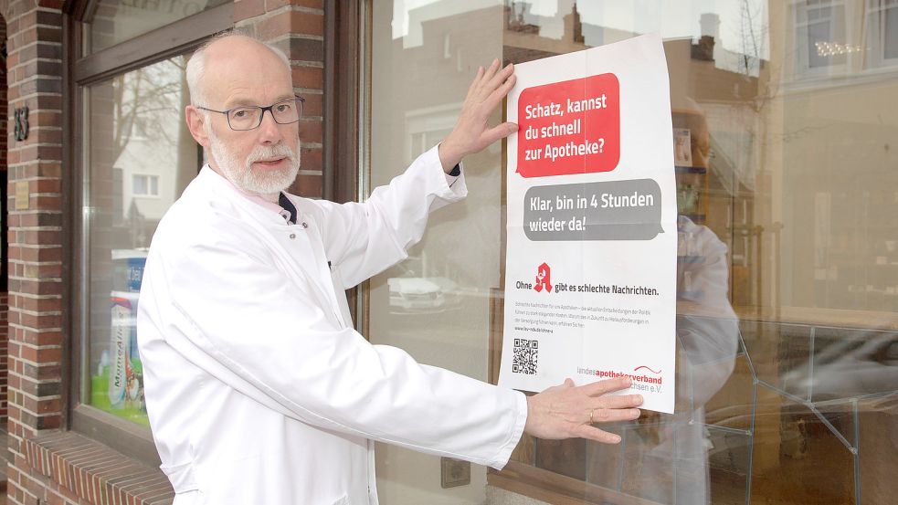 Berend Groeneveld, Vorsitzender des Landesapothekerverbandes, hängt an seiner Norder Rats-Apotheke ein Plakat auf. Mit den markigen Sprüchen möchte der Verband auf die schwierige Situation der Apotheken aufmerksam machen. Foto: LAV/Fotostudio Ekkenga