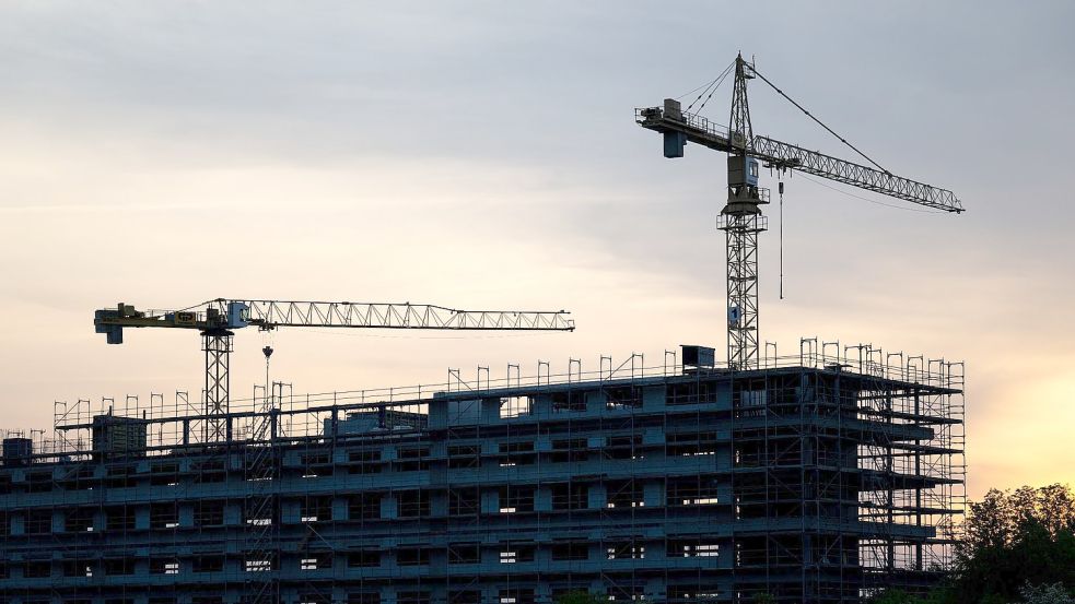 Kräne stehen hinter dem Rohbau für ein Bürogebäude auf einer Baustelle. Die Flaute am Bau hat sich auch im März fortgesetzt. Foto: Hendrik Schmidt/dpa