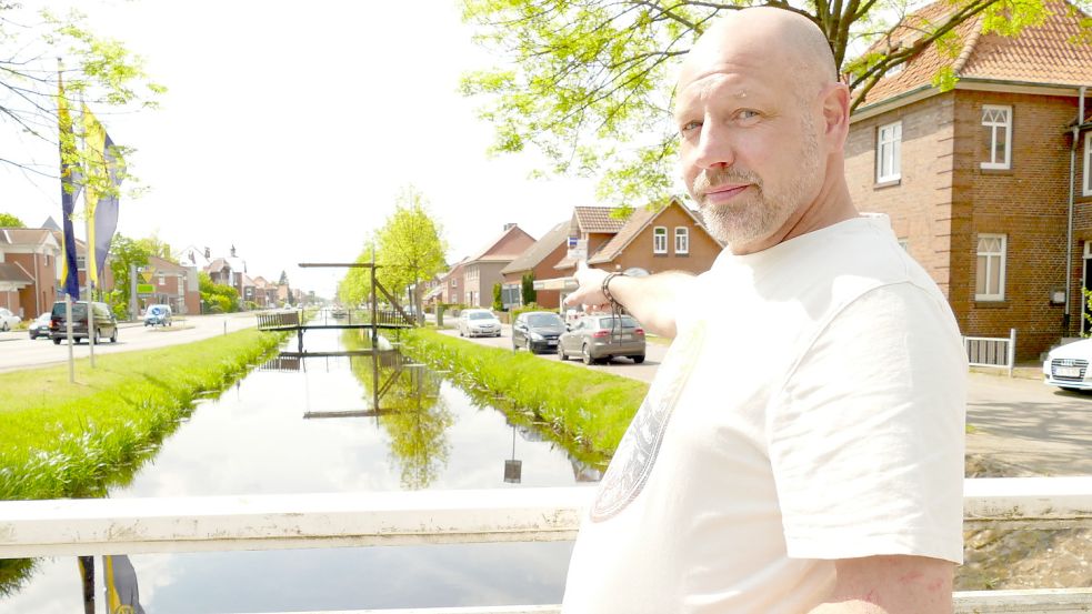 Johan Veen steht am Kreisel in Rhauderfehn und zeigt den Rajen-Kanal hoch. Auf der schmalen Seite (rechts) hatte eine verzweifelte Mutter gestanden, deren Baby im Kinderwagen ins Wasser gerollt war. Der Handwerker war auf der anderen Seite (links) mit einem Bulli unterwegs gewesen, als er die Frau sah. Der 52-jährige Niederländer sprang sofort ins Wasser und holte das Kind raus. Foto: Wieking