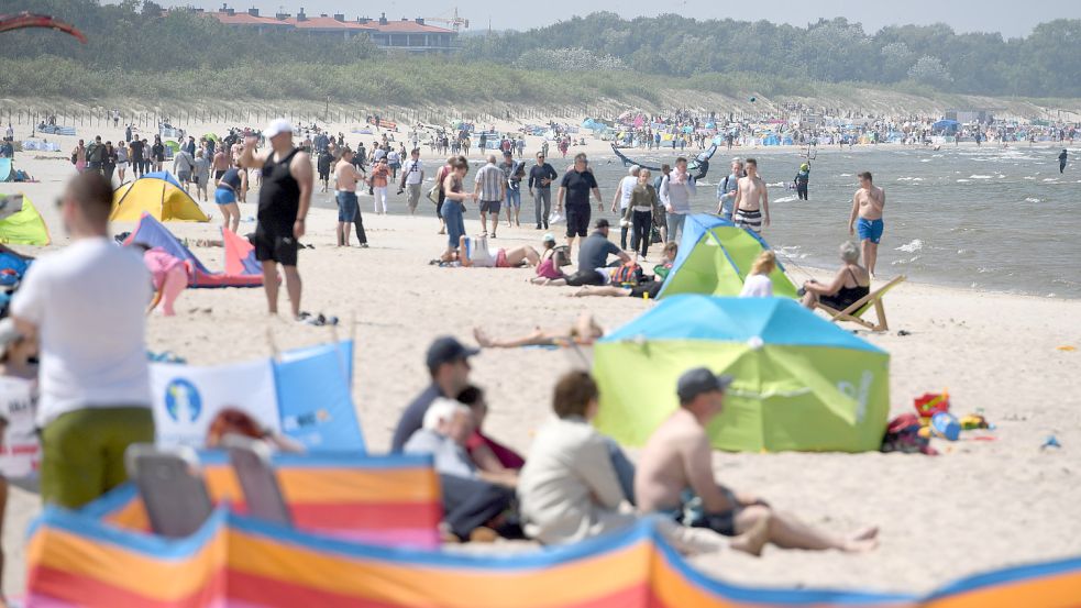 Touristen besuchen den Strand von Swinoujscie (Swinemünde) auf der polnischen Seite der Insel Usedom. Foto: dpa/Stefan Sauer